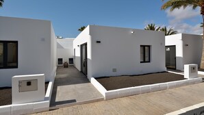 Un bâtiment moderne à l’extérieur épuré et blanc, doté d’un chemin piétonnier pavé et d’un petit espace jardin.