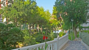 A stone pathway with a white balustrade, surrounded by lush greenery and trees. - Park Playa Levante by Interhome (Benidorm)