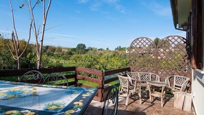 Une terrasse extérieure avec une table et des chaises, une clôture en bois et une vue sur un paysage verdoyant.