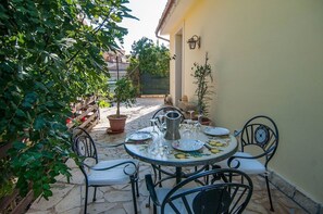 Une terrasse extérieure avec une table ronde mise pour le repas, entourée de chaises.