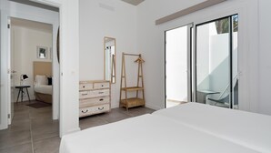 A bedroom with a bed, a dresser, a hanging rack, and a sliding glass door to a balcony. - Suite Costa Kenia close to Playa Bastian with Pool By PVL (Costa Teguise)