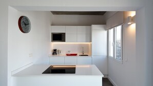 A modern kitchen with white cabinetry, a built-in microwave, a coffee maker, and a red tray. - Suite Costa Kenia close to Playa Bastian with Pool By PVL (Costa Teguise)