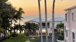 Ein Resort mit Pool, Palmen und Blick auf den Ozean bei Sonnenuntergang.