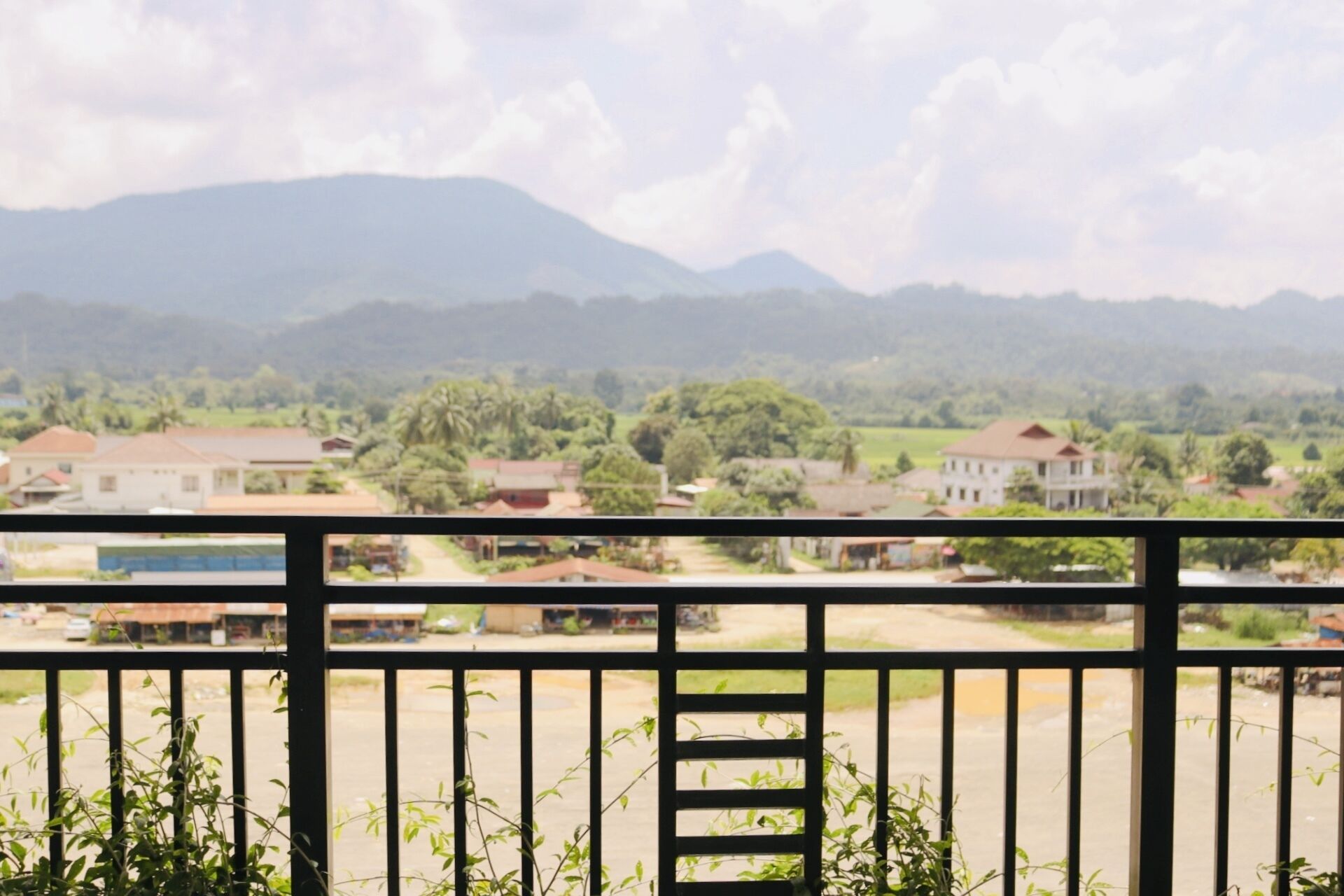 A balcony with a view of a residential area, houses, and mountains in the background.