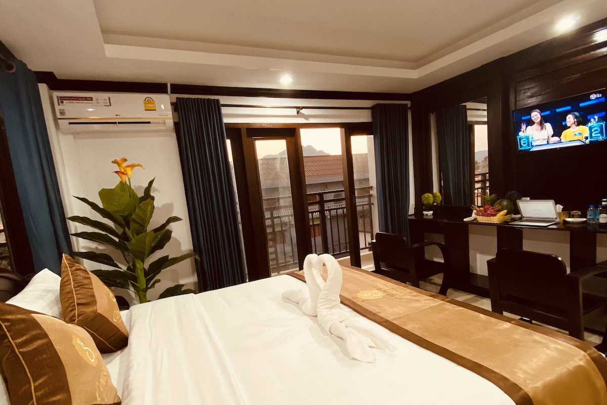Una habitación de hotel con una cama grande, un escritorio, un televisor y un balcón con vistas.