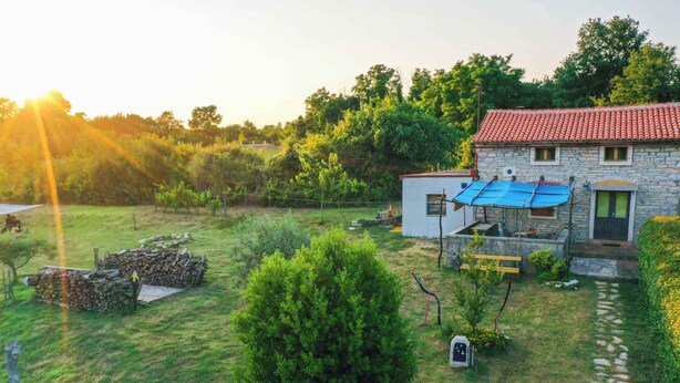 A stone house with a red-tiled roof, a small garden, and a solar panel. - Holiday home mit Terrasse und Klimaanlage (Petehi)