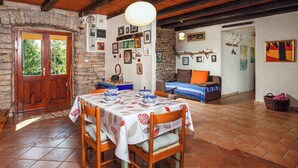 A rustic dining area with a wooden table and chairs, stone walls, and a stone fireplace. - Holiday home mit Terrasse und Klimaanlage (Petehi)