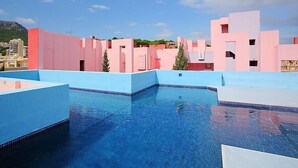 A swimming pool with blue and pink buildings in the background. - Muralla Roja by Interhome (Calpe/Calp)