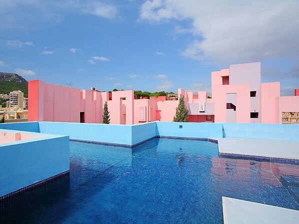 Una piscina con edificios azules y rosados al fondo.