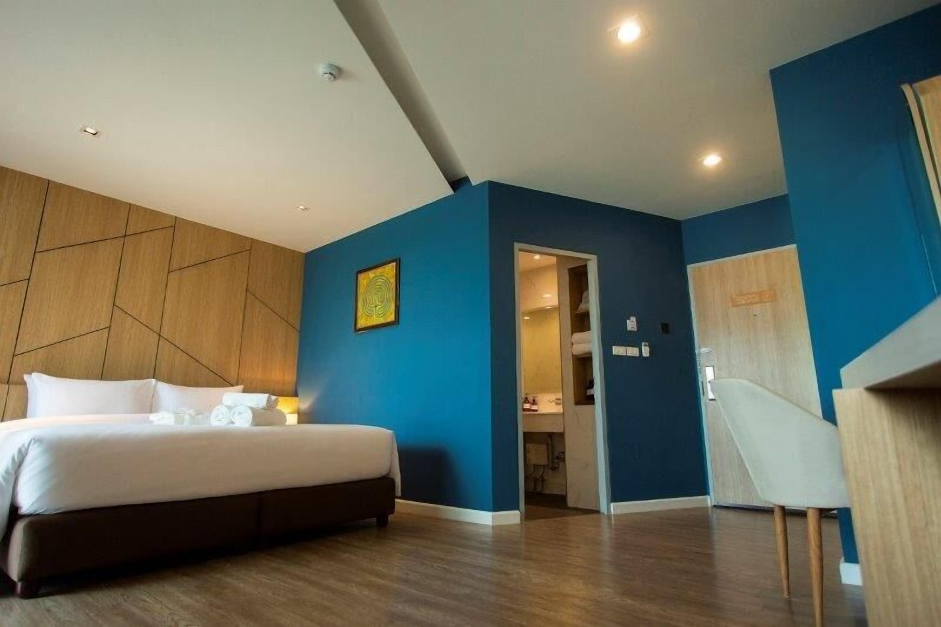 Una habitación de hotel moderna con una cama grande, un panel decorativo de madera y un panel decorativo azul.