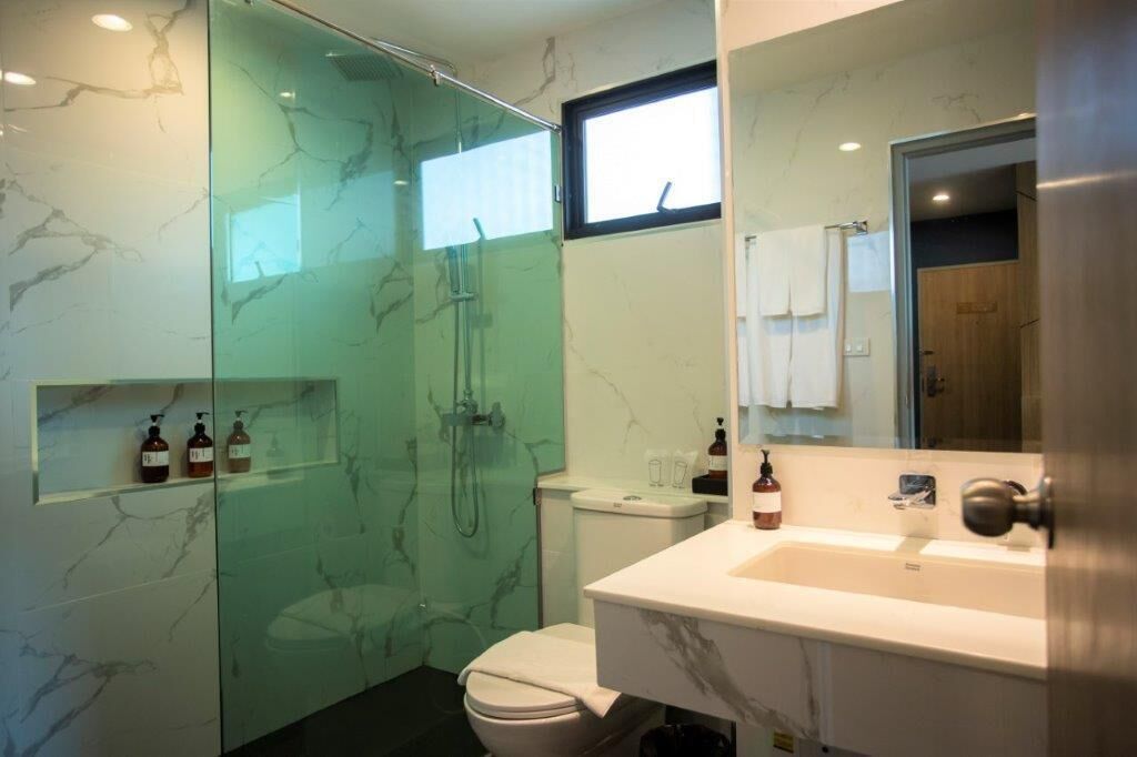A modern bathroom with a glass-enclosed shower, a white toilet, and a marble sink.