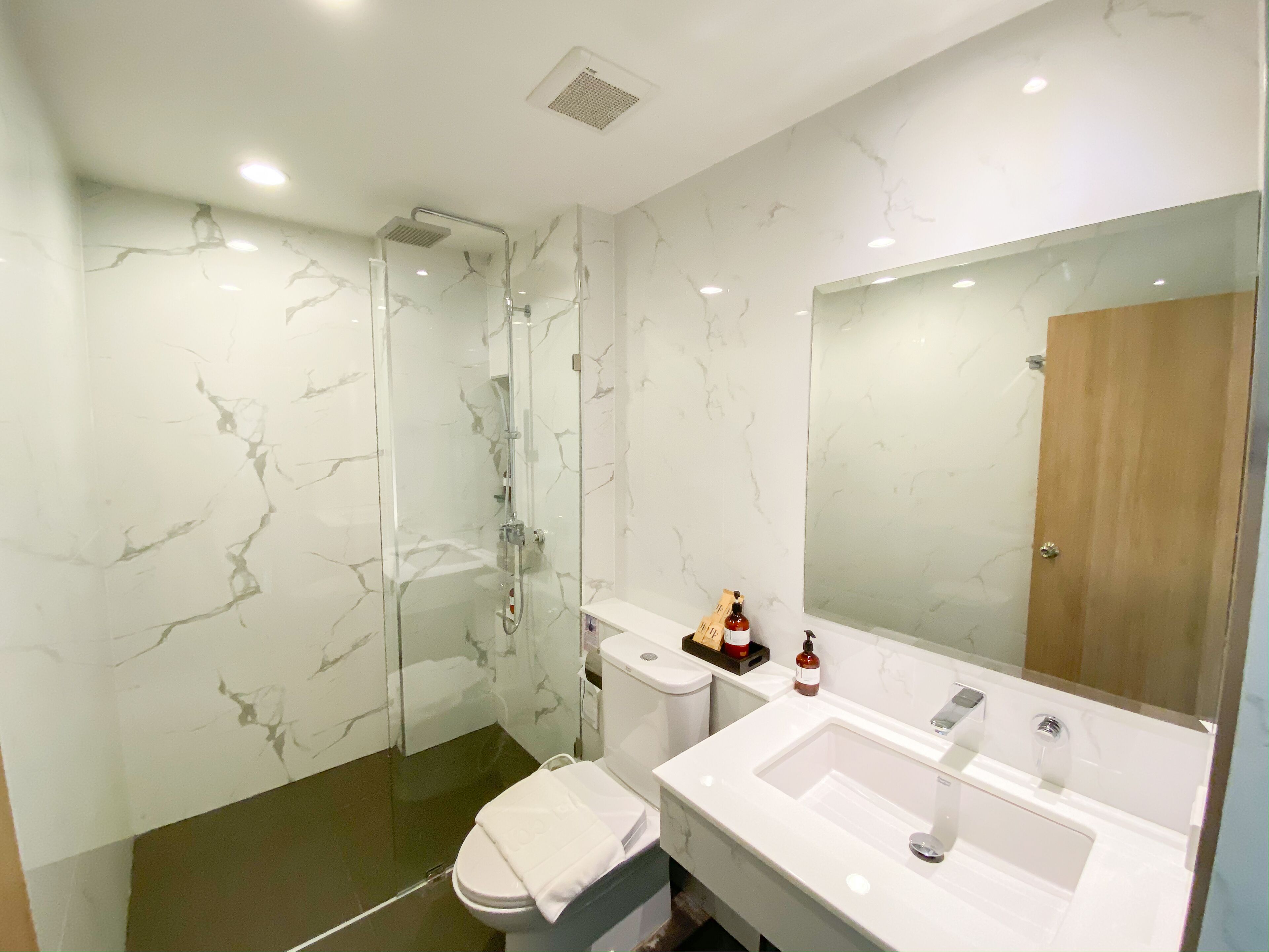 A modern bathroom with a glass-enclosed shower, a white sink, and a large mirror.