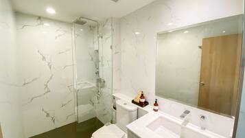 A modern bathroom with a glass-enclosed shower, a white sink, and a large mirror.