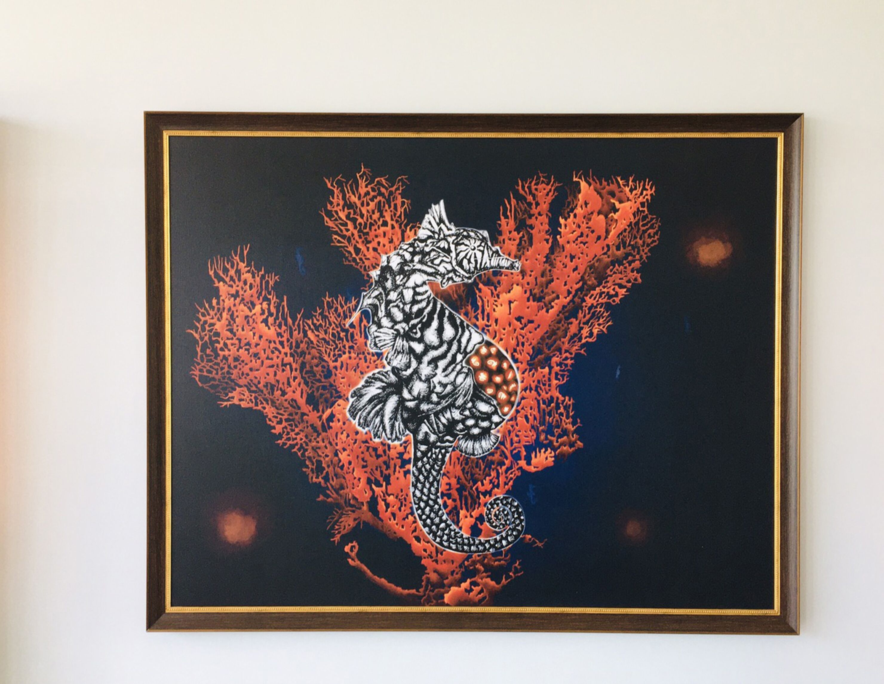 Une œuvre d’art encadrée représentant un hippocampe et des coraux sur un fond noir.