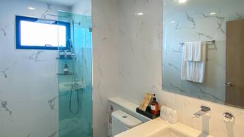 Een moderne badkamer met een douchecabine van glas, een wit toilet, een ruime wastafel en een spiegel met een handdoek aan de muur.