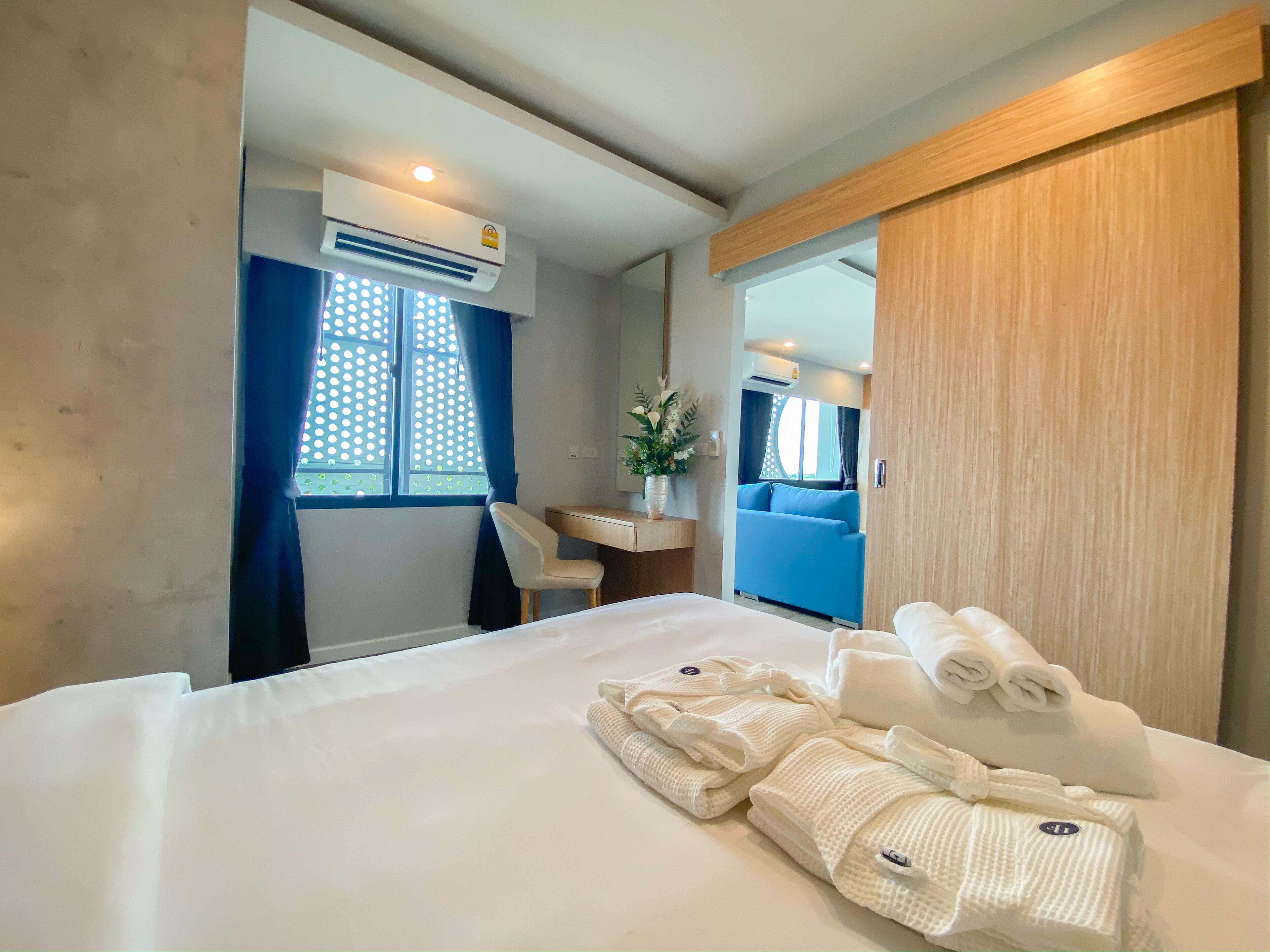 Una habitación de hotel con cama, escritorio, silla, espejo y equipo de aire acondicionado.