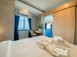 Una habitación de hotel con cama, escritorio, silla, espejo y equipo de aire acondicionado.