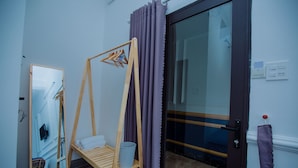 A room with a wooden swing chair, a mirror, a door with purple curtains, and a tiled floor. - Rome Hostel (Tuy Hoa)