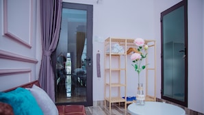 A modern room with a sofa, a small table, a wooden shelf, and a glass door leading to a balcony. - Rome Hostel (Tuy Hoa)
