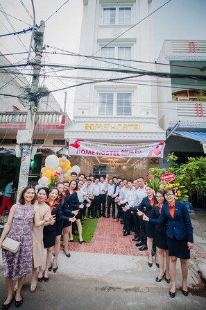 A group of people standing in front of a building with a sign that reads "ROME HOSTEL". - Rome Hostel (Tuy Hoa)