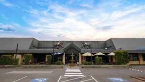 A building with a large parking lot, a fountain, and two horse statues. - Blacktown Tavern (Blacktown)