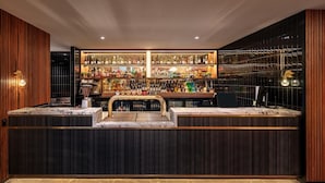 A bar area with a marble countertop, shelves of liquor bottles, and a modern design with wooden panels and recessed lighting. - Blacktown Tavern (Blacktown)
