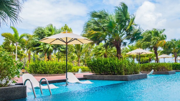 A swimming pool with palm trees and umbrellas. - Timurbay Seafront by My Seasons (Kuantan)