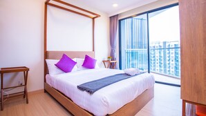 A modern hotel room with a large bed, wooden headboard, and a view of the city through floor-to-ceiling windows. - Timurbay Seafront by My Seasons (Kuantan)