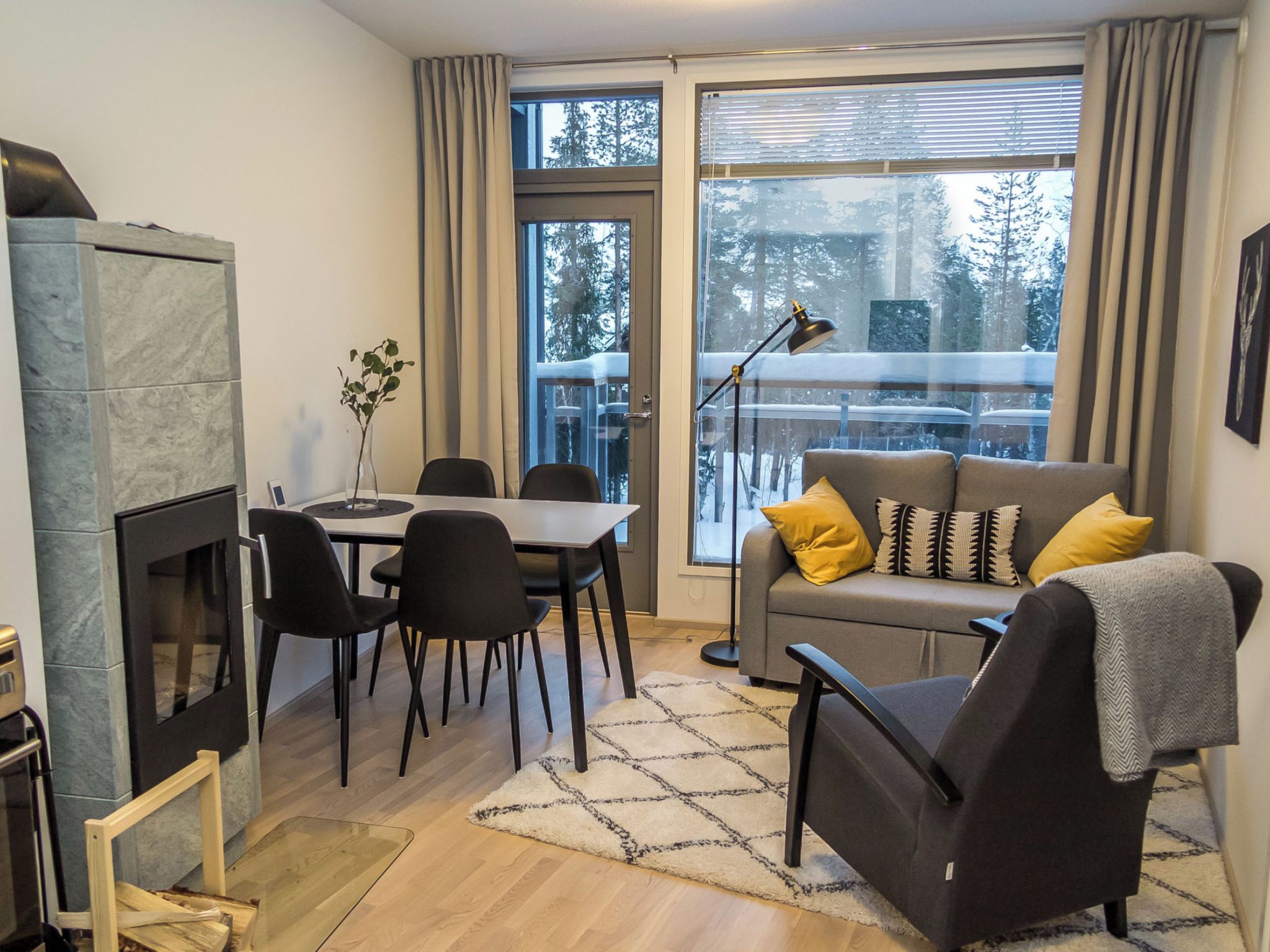 A modern living room with a fireplace, dining area, and a sofa with cushions.