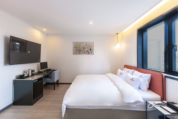 A modern hotel room with a bed, desk, and TV.