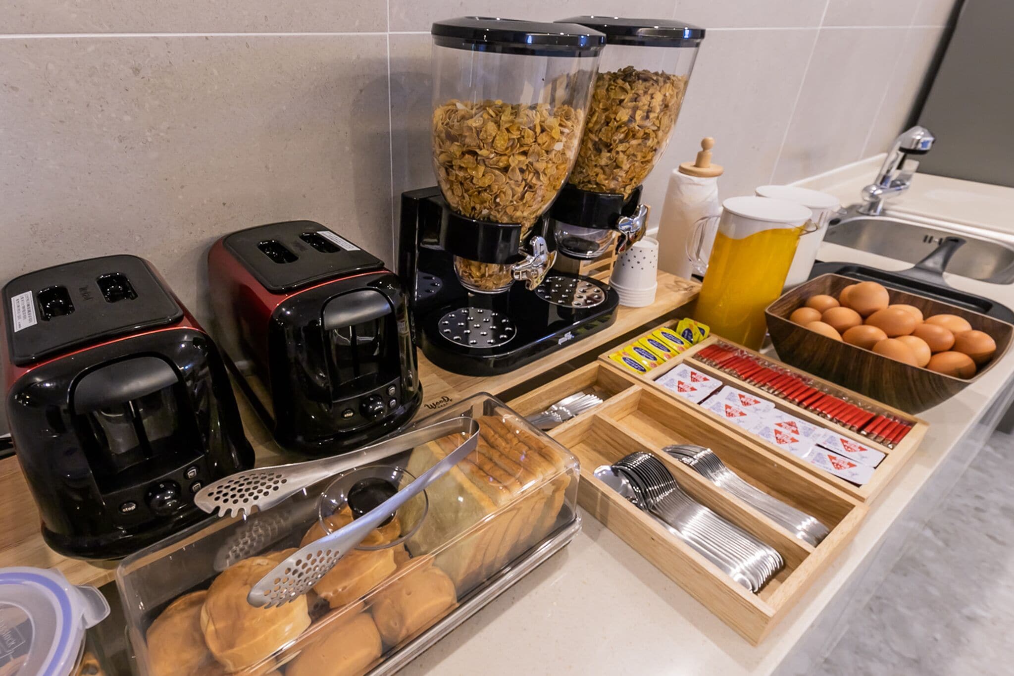 Una encimera de cocina con tostadoras, cafetera, licuadora, un panera y un bol de huevos.