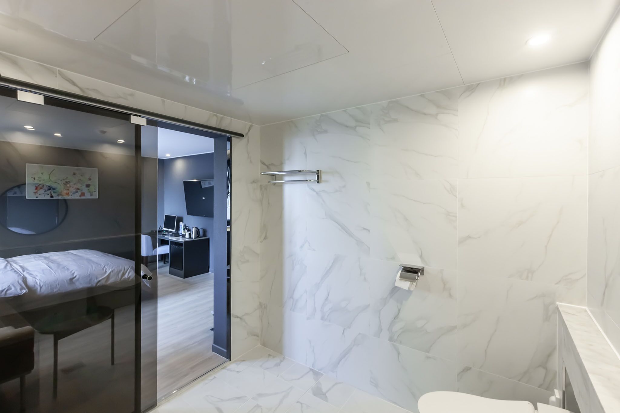 A modern bathroom with a shower, toilet, and a glass-enclosed sleeping area.
