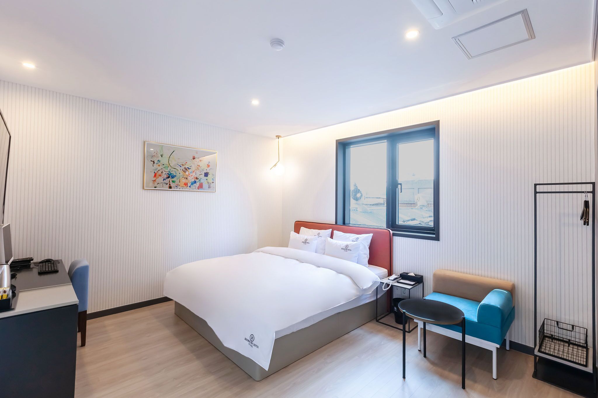 Une chambre d’hôtel moderne équipée d’un lit, d’un bureau, d’une chaise et d’un petit canapé.