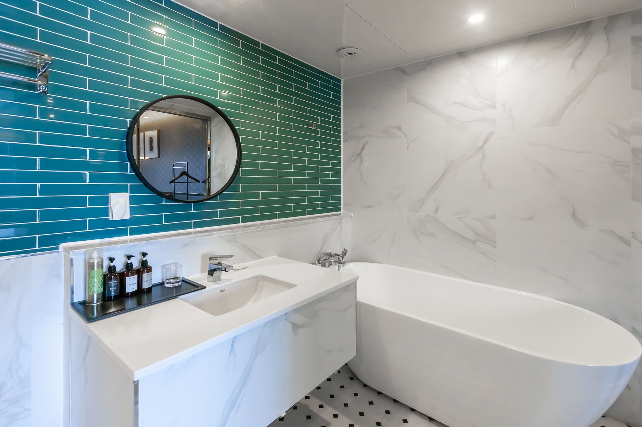 A modern bathroom with a white marble sink, a freestanding bathtub, and a mirror above the sink.