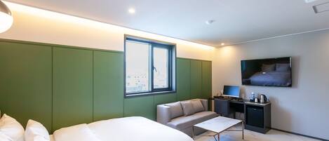 Habitación de hotel con dos camas, un sofá, un escritorio, un televisor y una ventana con vistas.