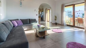 Amplia sala de estar con un sofá moderno, una mesa de centro de vidrio y vistas al patio exterior a través de puertas correderas grandes.