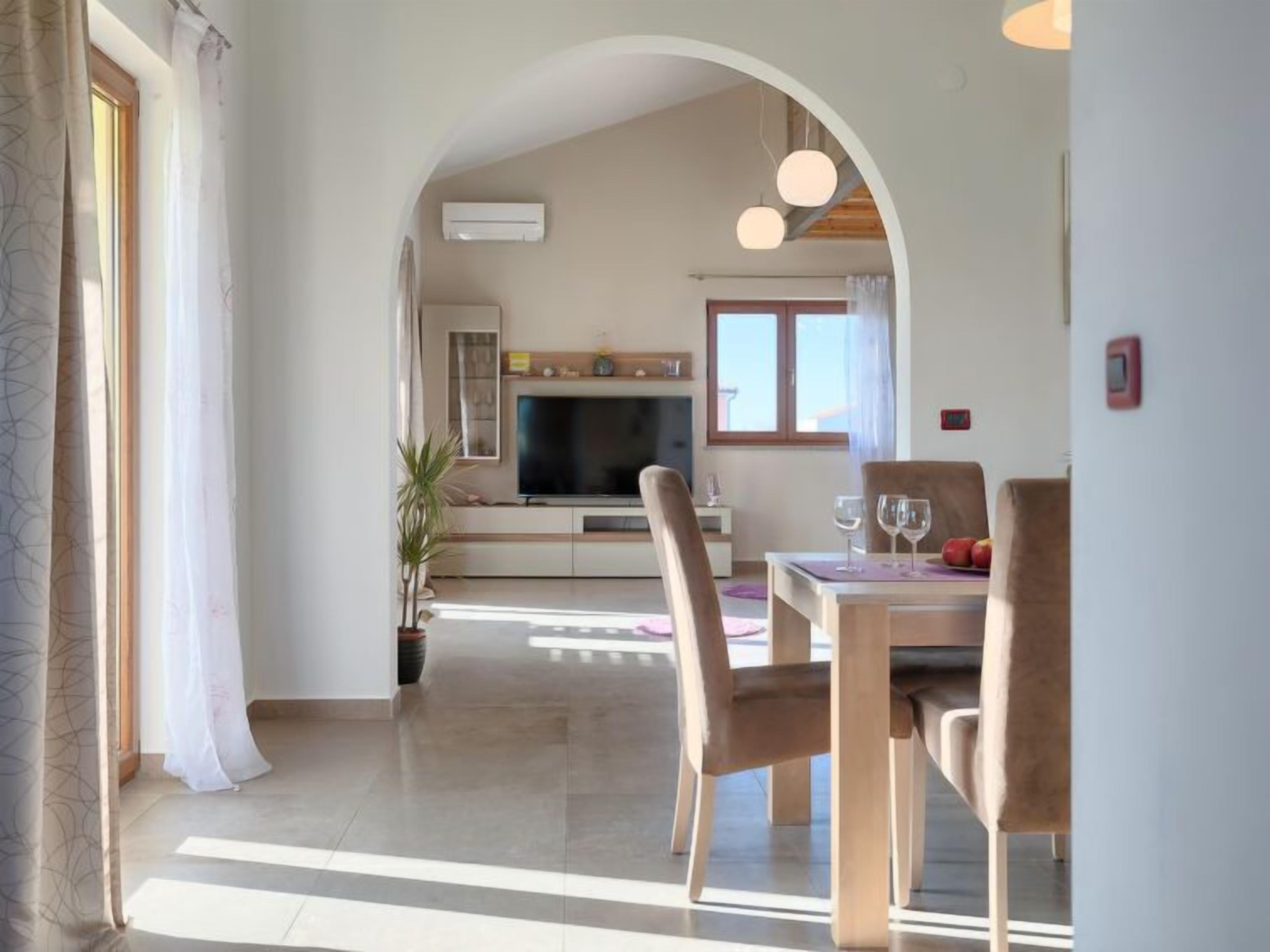 Ein modernes Wohnzimmer mit Fernseher, Sitzgelegenheit und Esstisch.