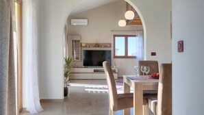Una sala moderna con televisor, zona de estar y mesa de comedor.