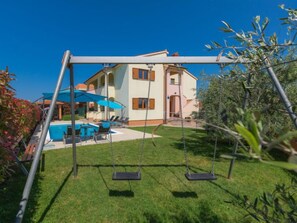 Une maison à deux étages avec une piscine et un espace extérieur aménagé pour se détendre.