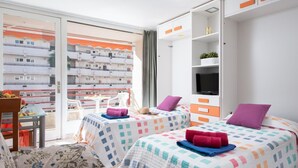 Ein Hotelzimmer mit zwei Betten, einem Fernseher und einem Balkon mit Blick auf die Stadt.