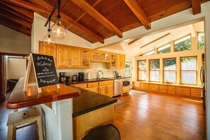 Una cocina con armarios de madera, una barra y un letrero en una pizarra.