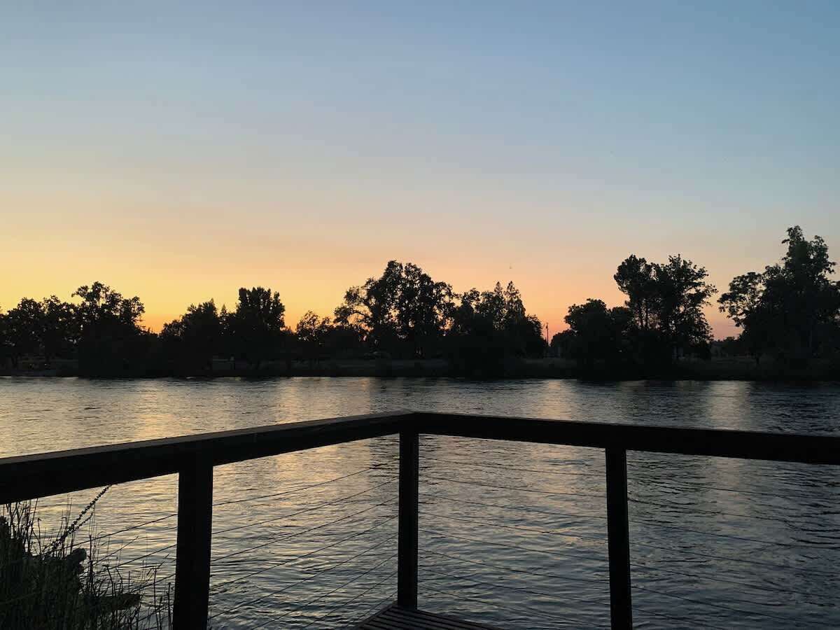 Une rivière avec une rambarde en bois au premier plan.
