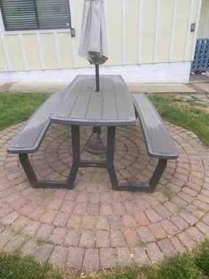 A picnic table with a canopy, surrounded by a brick patio.