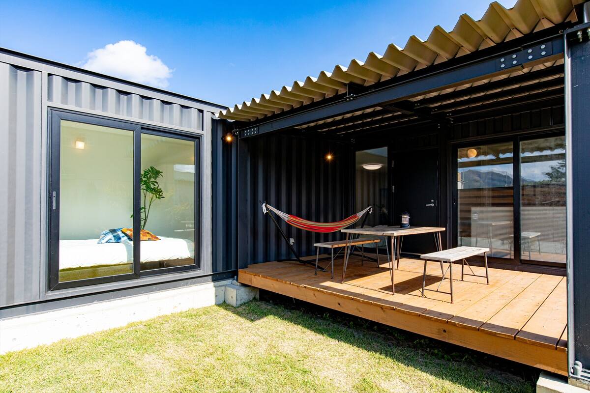 Eine moderne Außenpatio mit einer Hängematte, einem Tisch und einer Bank.