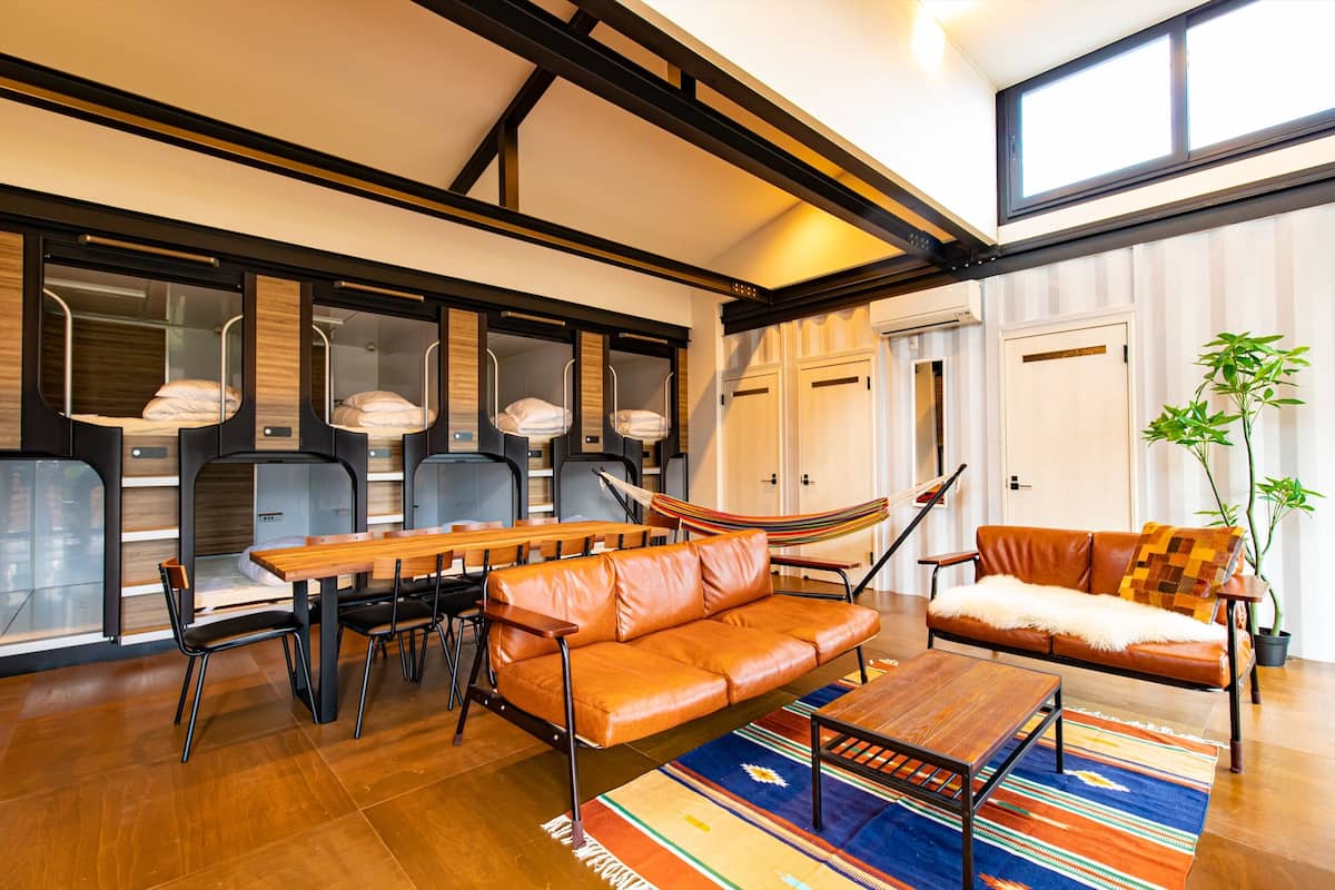 Ein modernes Wohnzimmer mit Esstisch aus Holz, Ledersofa und einer Hängematte.