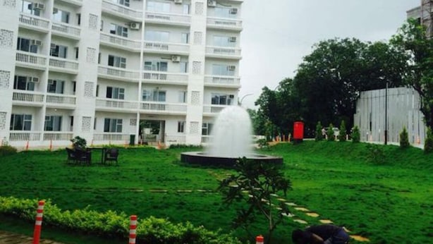 A multi-story building with balconies and a fountain in the courtyard. - Comfort of Home with Nature at its best (Khopoli)