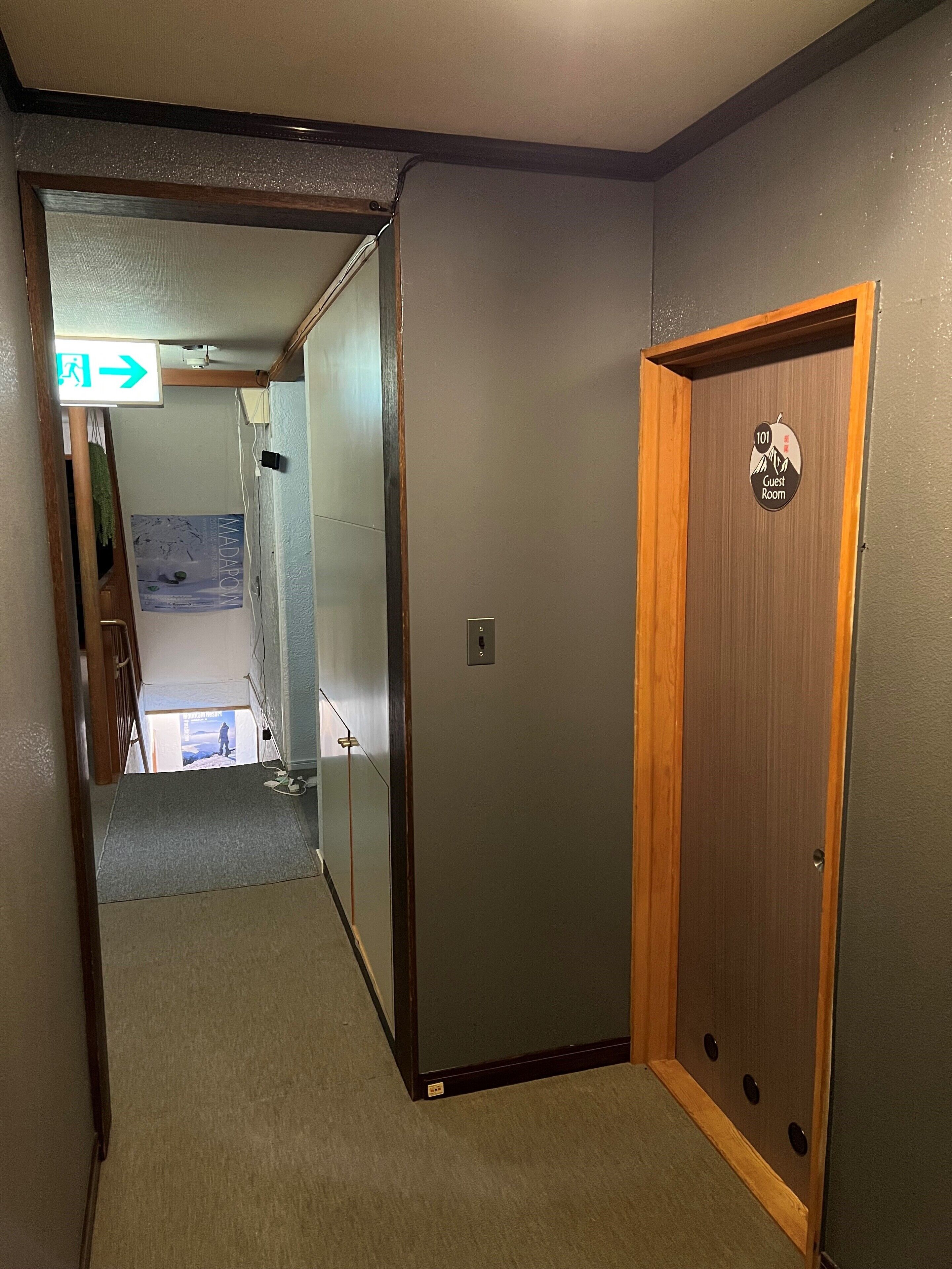 A hallway with a wooden door labeled "101 Guest Room" and a directional sign pointing to the right.