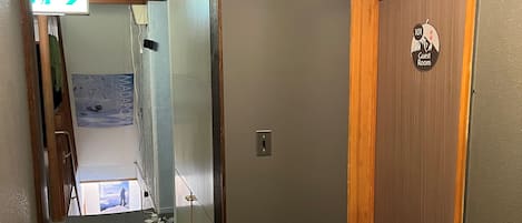 A hallway with a wooden door labeled "101 Guest Room" and a directional sign pointing to the right.