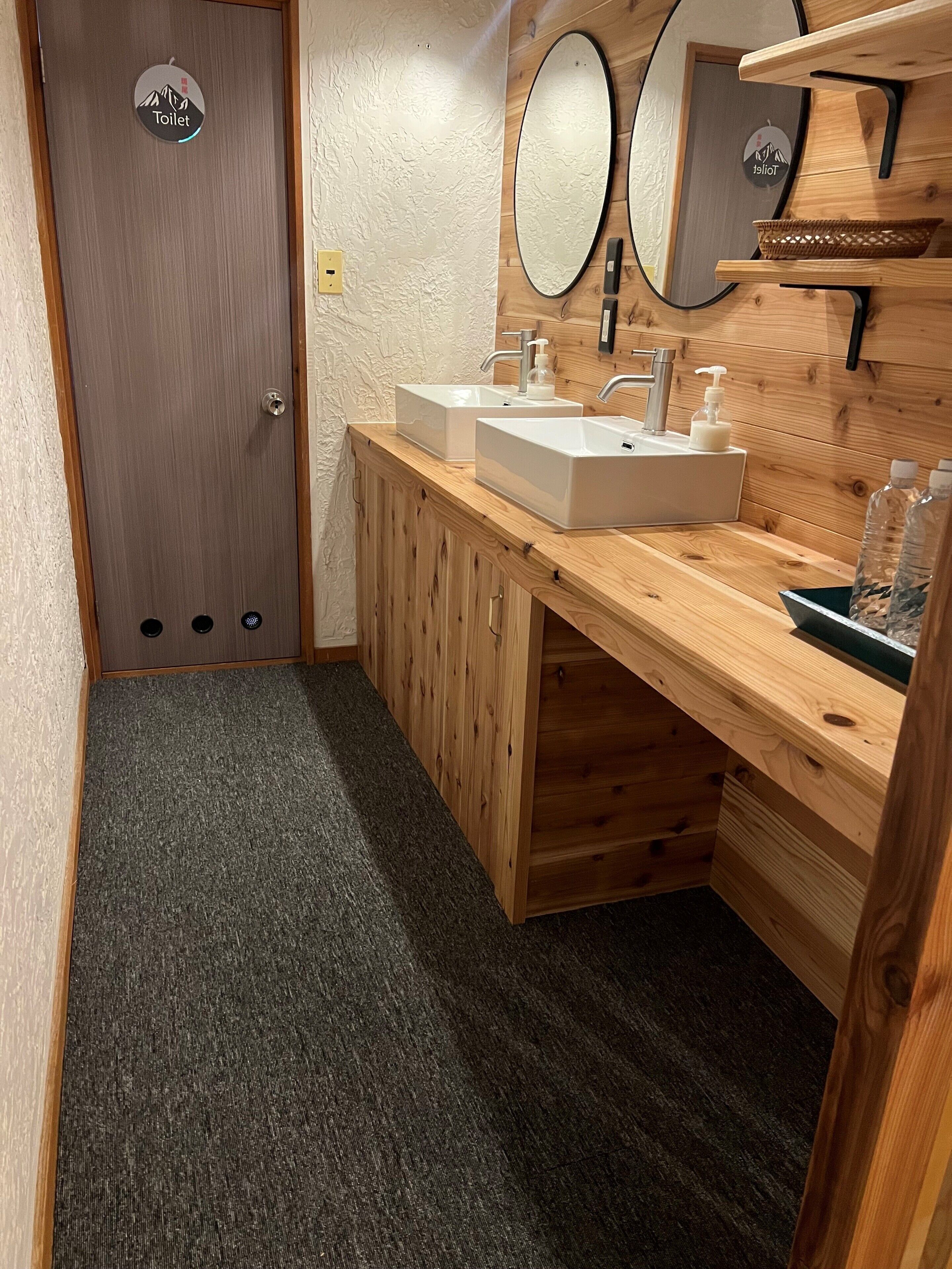 A bathroom with wooden cabinetry, a double sink, and a mirror.