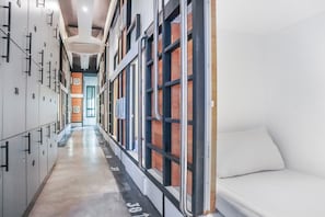 A hotel corridor with lockers, a bed, and a view of the outside. - Sleep Box Hostel Suratthani (Surat Thani)